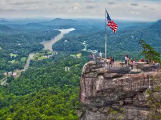 Chimney Rock overlooking Lake Lure, with American Flag standing proud in the foreground 