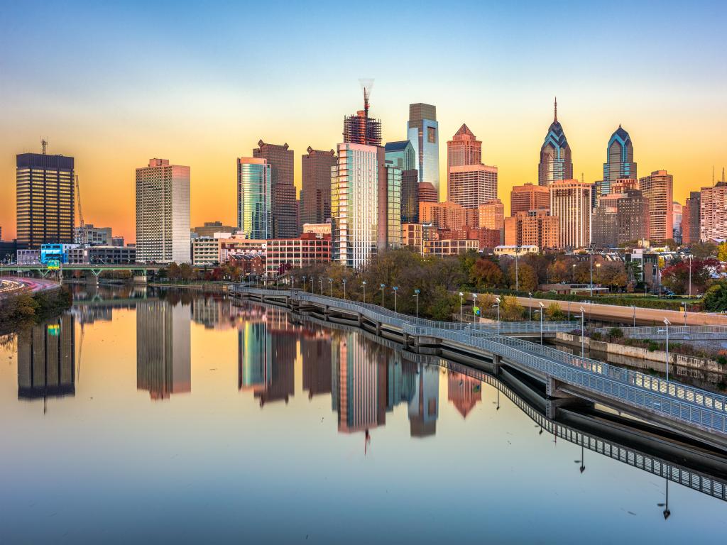 Philadelphia, Pennsylvania showing the downtown skyline at dusk in the background at the Schuylkill River in the foreground with the buildings reflecting in the water.