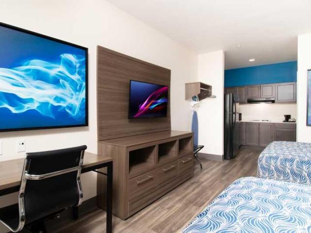 Clean and modern interior of Palace Inn El Paso bedroom, with kitchenette, double beds and wall storage  
