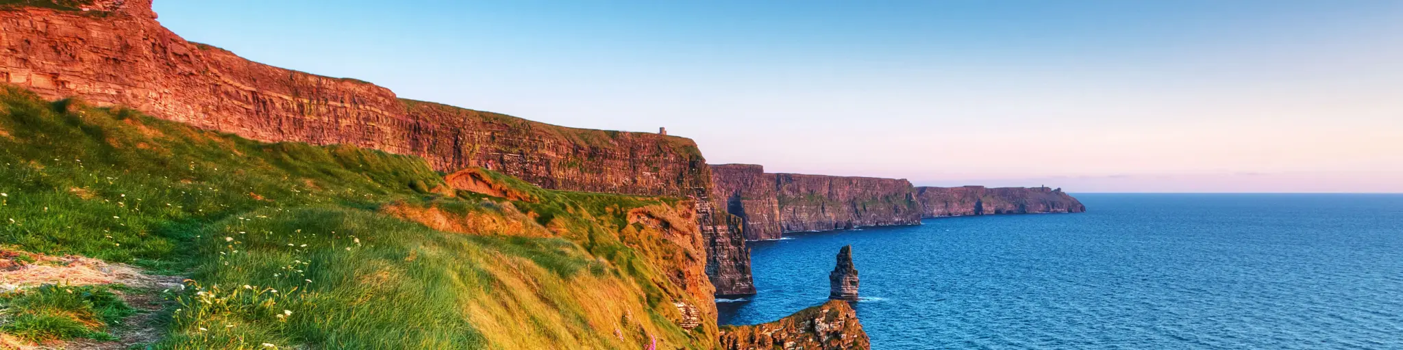A view out towards the jagged cliffs at the Cliffs of Moher, Ireland, at sunset