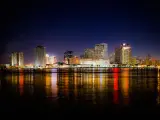 New Orleans, Louisiana, USA skyline at night with the city lights reflected in the dark water in the foreground.