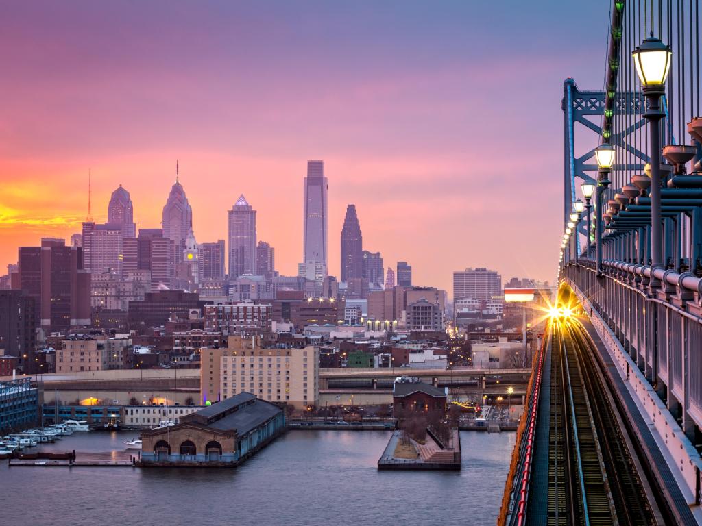 Hazy purple sunset over the city with a train crossing the railway bridge.