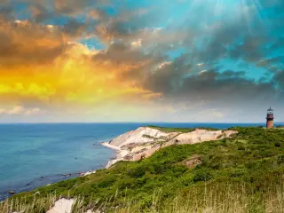 Sun setting over the water, a lighthouse in view
