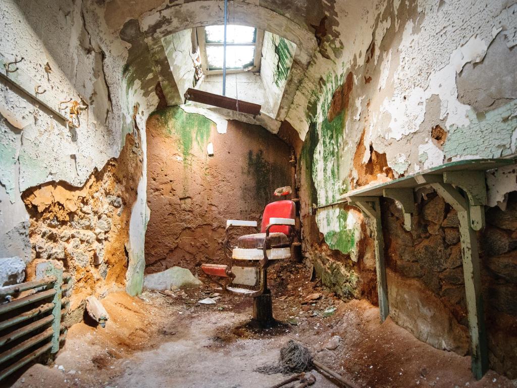 Old red seat in a decrepit room with a skylight that is falling apart