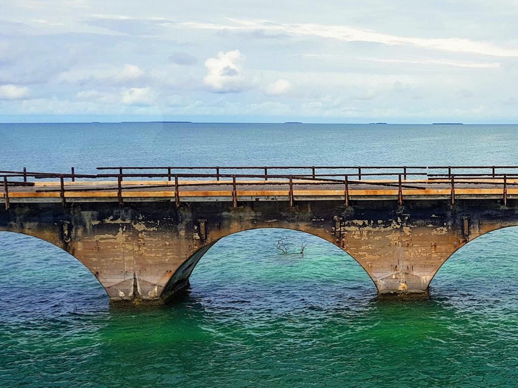 Beautiful view of old abandoned Overseas Railroad, rusted brown railway bridge with arcs across blue ocean water