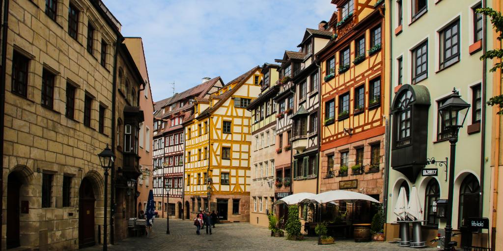 A view down Weißgerbergasse in Nuremberg with colourful timber framed houses either side and a cafe in the foreground