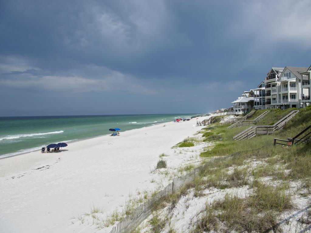 Rosemary Beach, Florida, USA with beach houses and steps leading the sand dunes, white sandy beach and sea with dark clouds above.