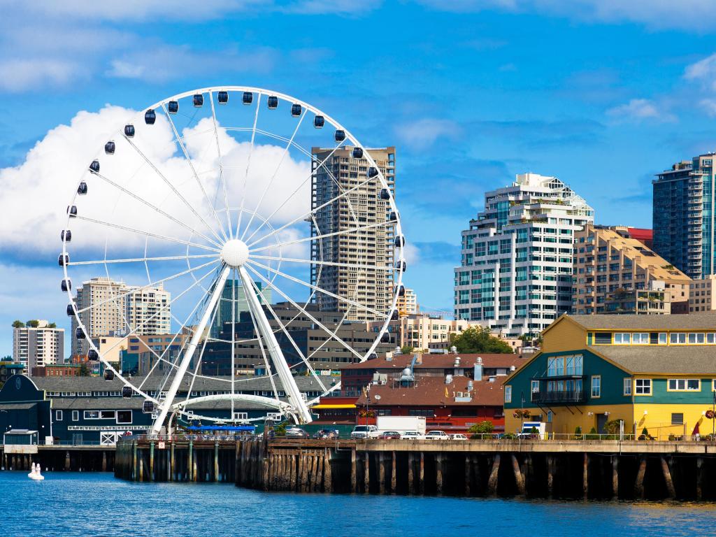 Seattle ferris wheel, waterfront and skyline on a bright sunny day with blue sky and clouds. View is from the water. Close up.