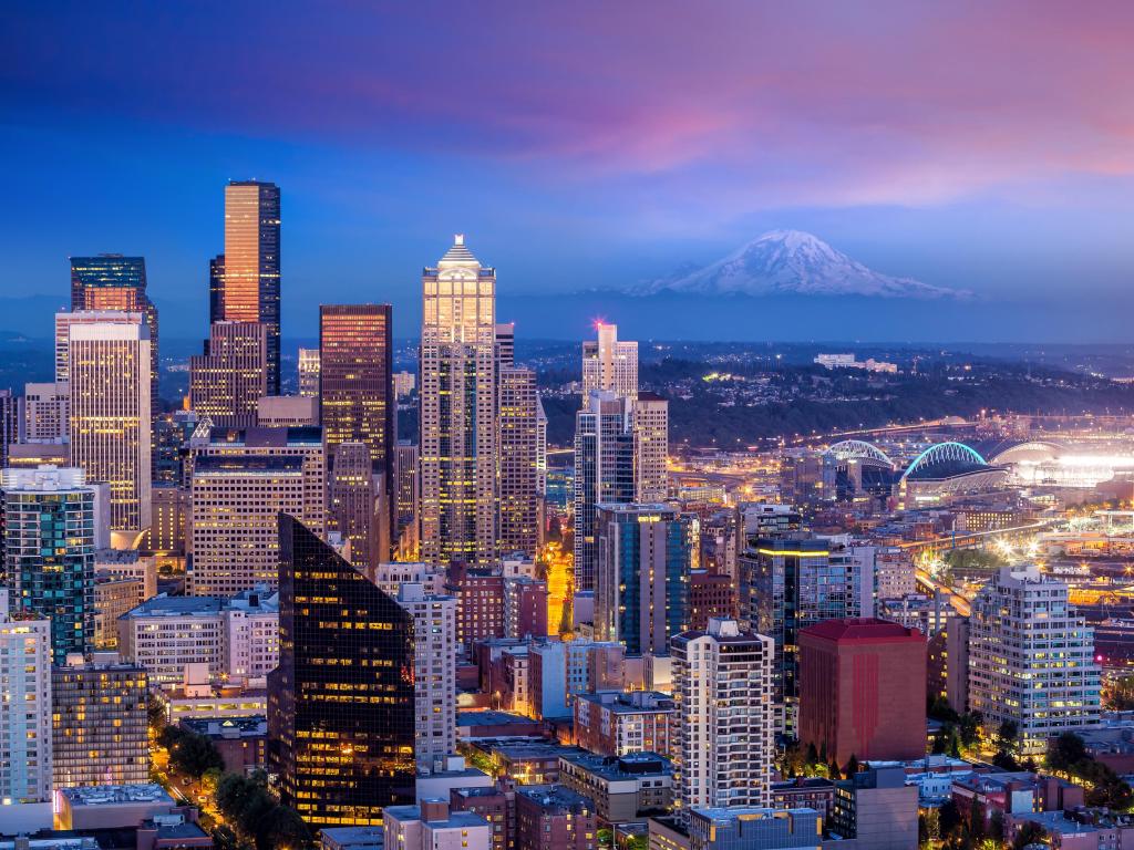 Seattle, USA with the city skyline at sunset and the faint outline of a mountain in the distance.