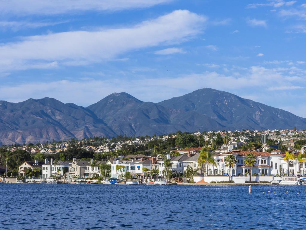 View across waterfront at Lake Mission Viejo, with properties and picturesque hills in the background, dotted with palm trees