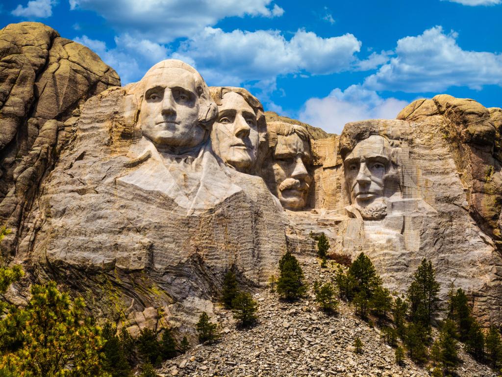 Mount Rushmore, South Dakota, USA with the sculptures of Four United States Presidents at sunrise against a blue sky.