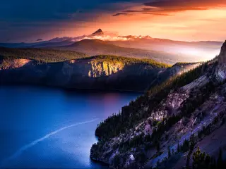 Crater Lake National Park, Oregon taken from Mt Thielsen at Sunrise and looking down on the lake and hills in the distance with a dramatic red sky.