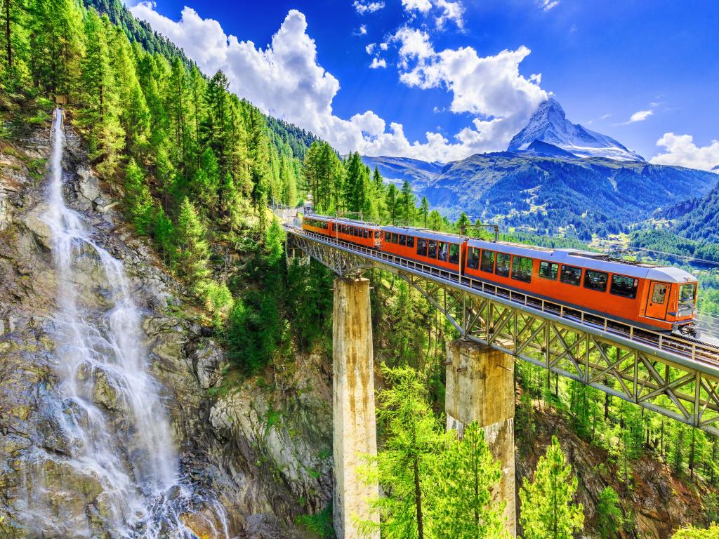 Zermatt, Switzerland. Gornergrat tourist train with waterfall, bridge and Matterhorn. Valais region.