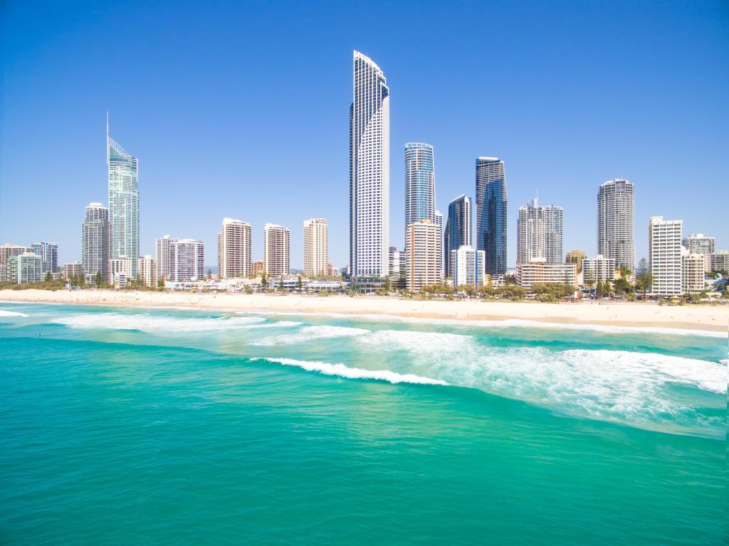 High rise buildings on the shore viewed across turquoise sea water in bright sunlight with clear blue sky