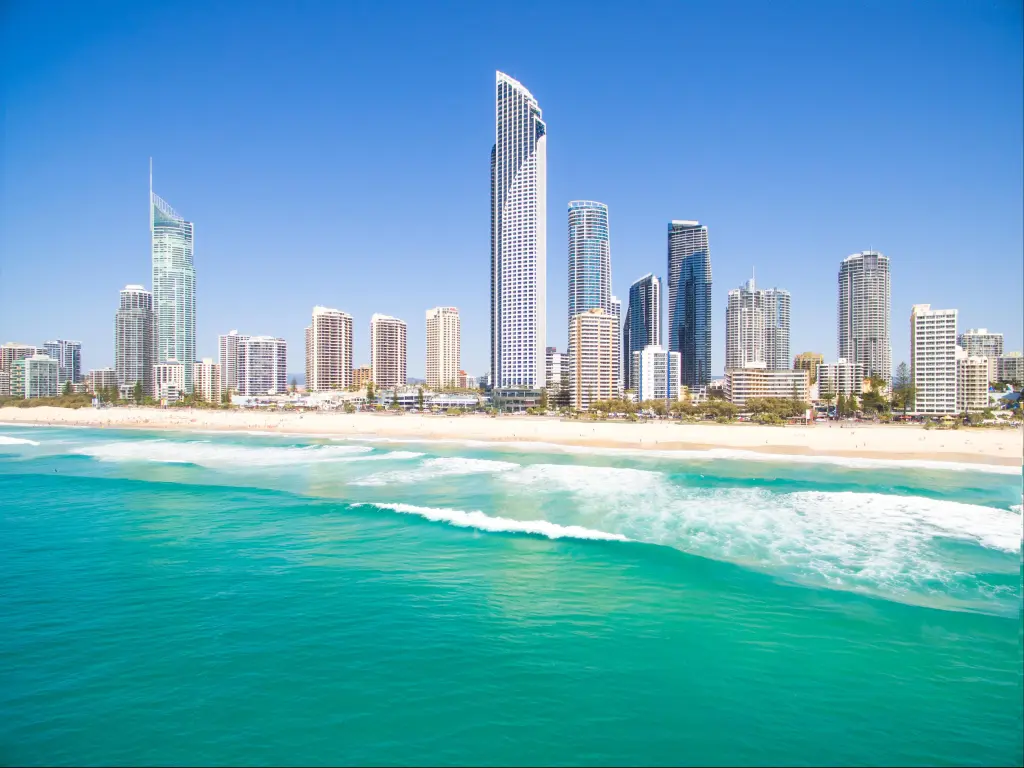 High rise buildings on the shore viewed across turquoise sea water in bright sunlight with clear blue sky