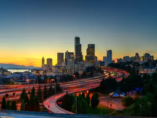 The view from Rizal Park of Seattle skyline during sunset with highway traffic motion.
