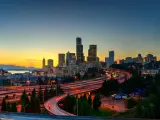 The view from Rizal Park of Seattle skyline during sunset with highway traffic motion.