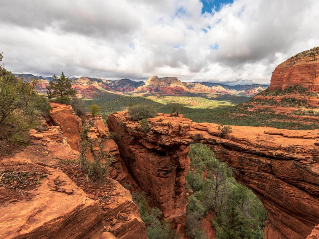 Devil's Bridge, Sedona, Arizona, USA taken on a cloudy day with red rock formations in the distance.