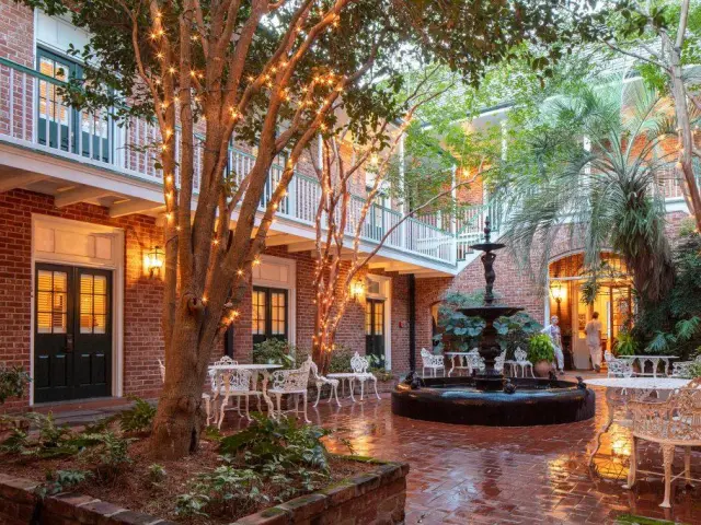 Outdoor courtyard with furniture, cobblestones, fountain and fairy lights in the trees, at Hotel Provincial, New Orleans