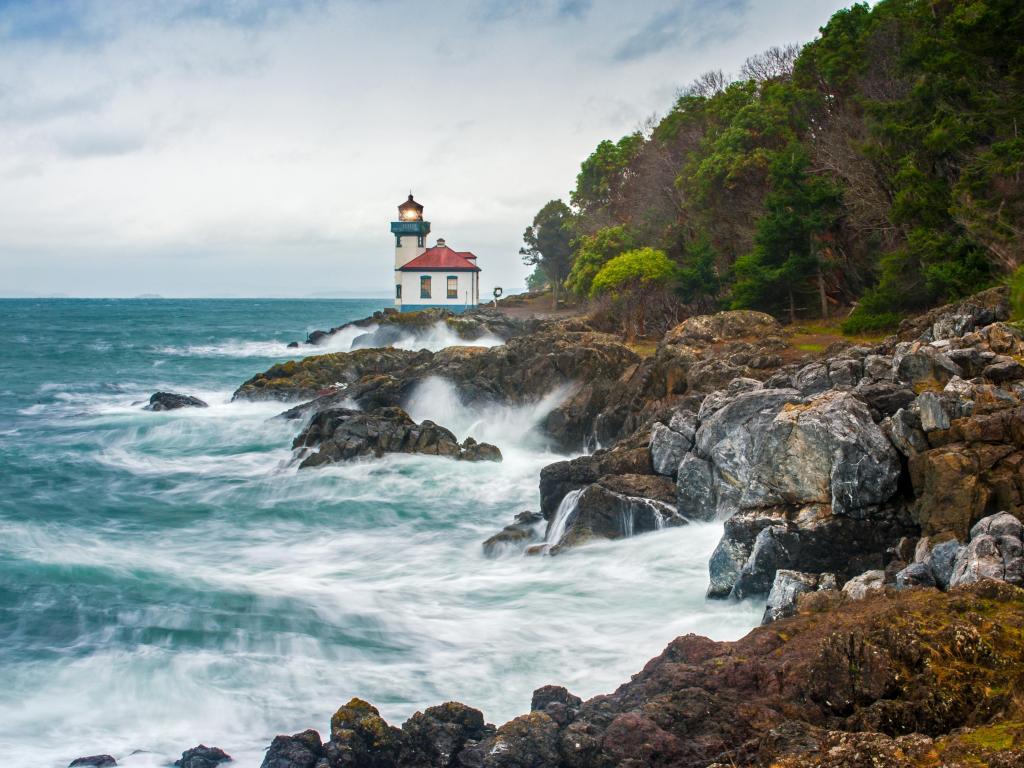 San Juan Island, Washington, USA with a view of Lime Kiln Lighthouse on a stormy day with waves crashing against the rocky coastline.