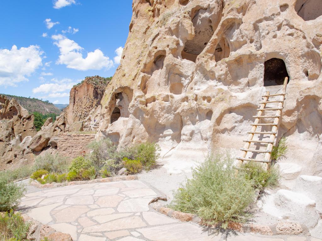 Bandelier National Monument in New Mexico, USA with a ladder leading to the cave entrances against the cliff face on a sunny day.