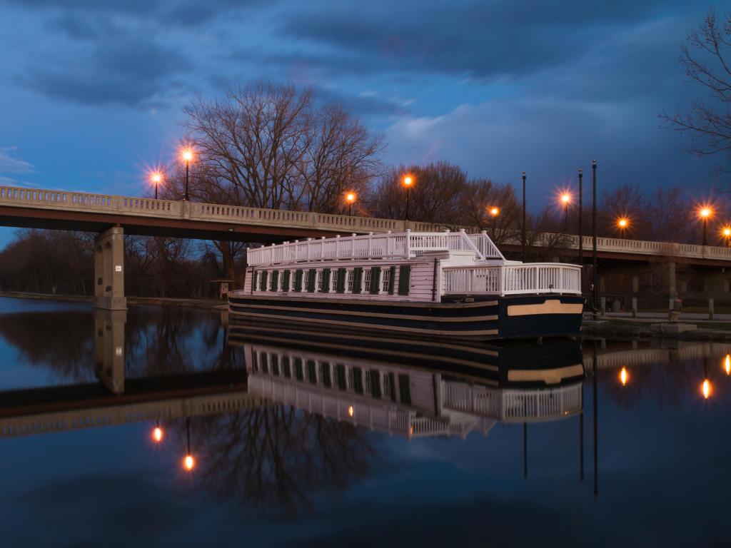 An old canal boat docked near a bridge at dusk