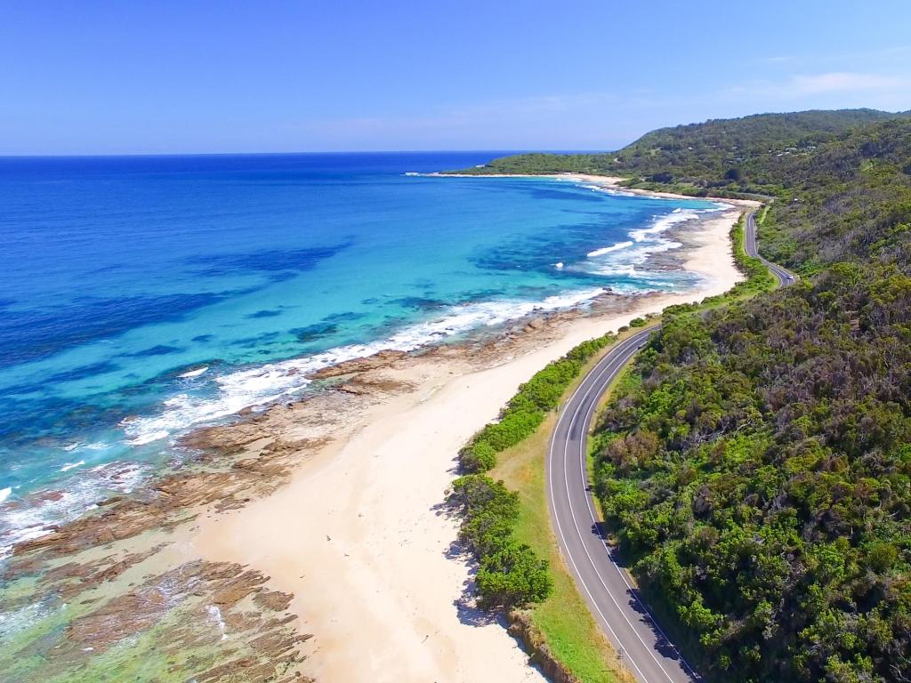 Panoramic view of the Great Ocean Road, Australia with the road running alongside the shoreline and a blue sky