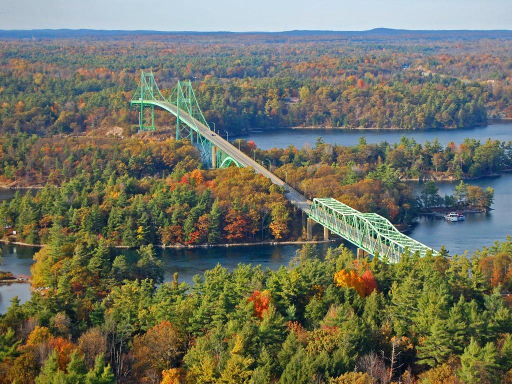 Green bridge crossing tree covered river islands in fall colors