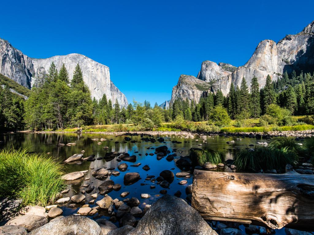 A lake at the bottom of a valley surrounded by mountains in Yosemite National Park, California