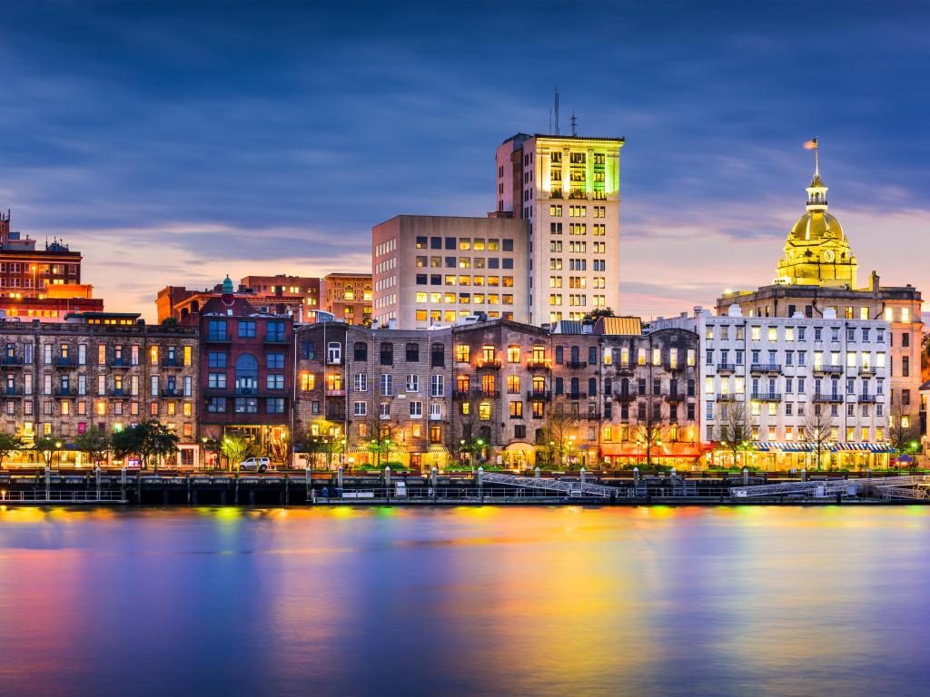 Savannah, Georgia, USA downtown skyline taken at early evening with the buildings reflecting in the water in the foreground.