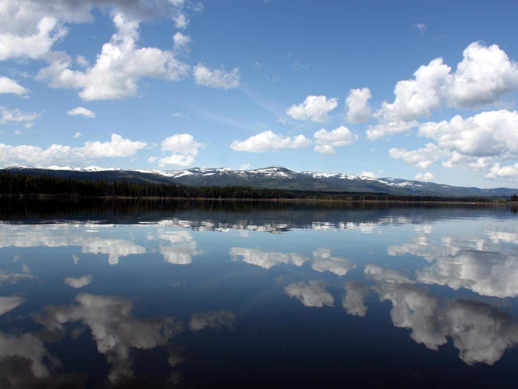 Seeley Lake, Montana, USA with cloud reflections on the lake taken on a sunny day with snow-capped mountains in the distance.