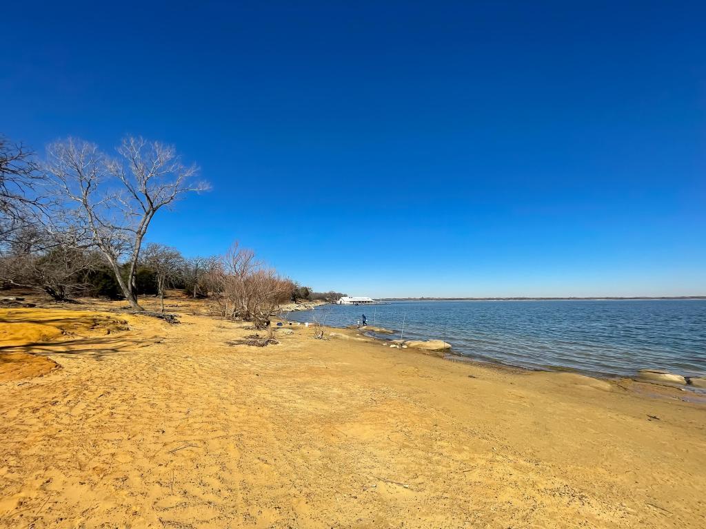 Golden sandy shoreline on the banks of Lewisville Lake, Texas, with a clear blue sky above