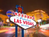Neon-lit sign that reads "Welcome to Fabulous Las Vegas Nevada" with colorful lights of the hotels behind it