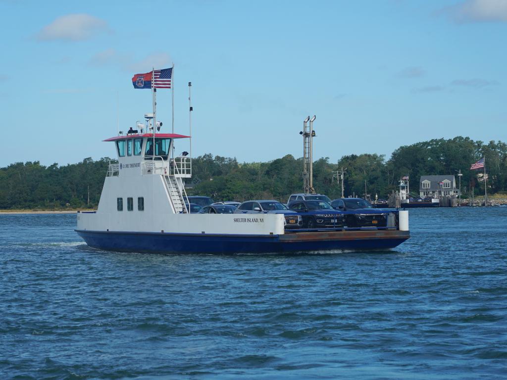 A ferry carrying cars and passengers from Shelter Island to Sag Harbor on a sunny day.