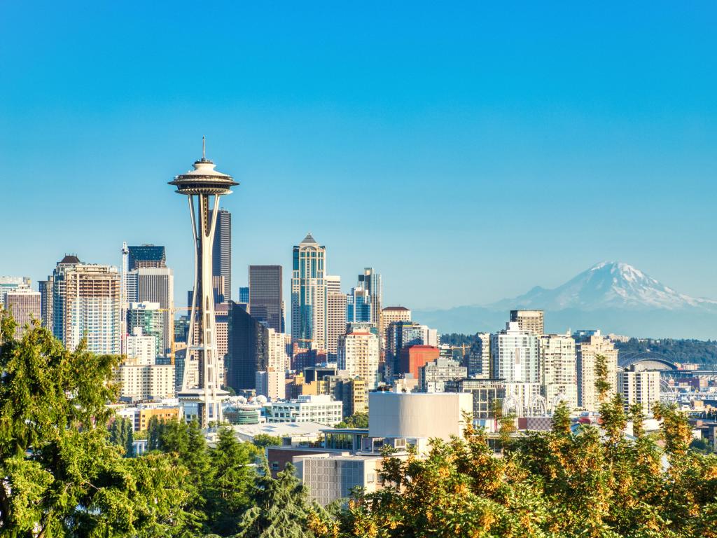 Seattle, Washington, USA with the cityscape and Mt. Rainier in the background on a sunny day with a clear blue sky.