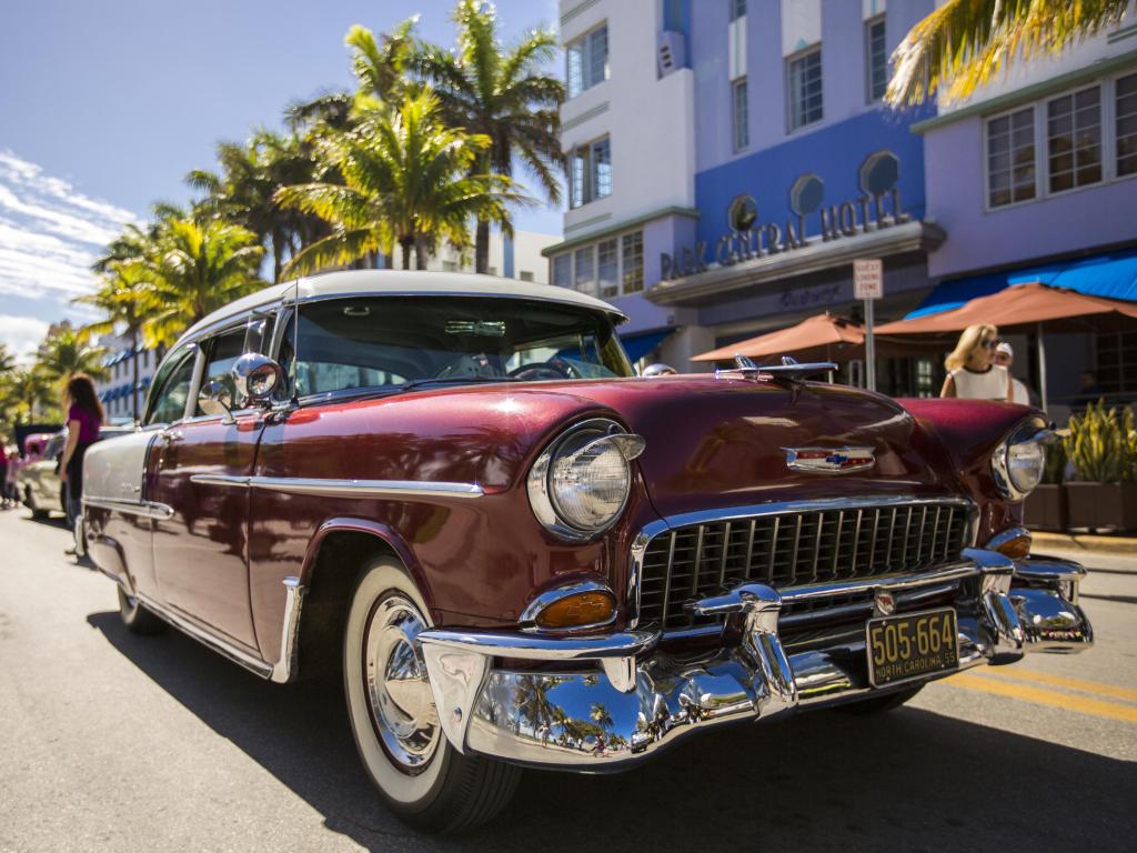 Close up shot of a vintage car at Art Deco Weekend festival in Miami Beach, with colorful store fronts behind