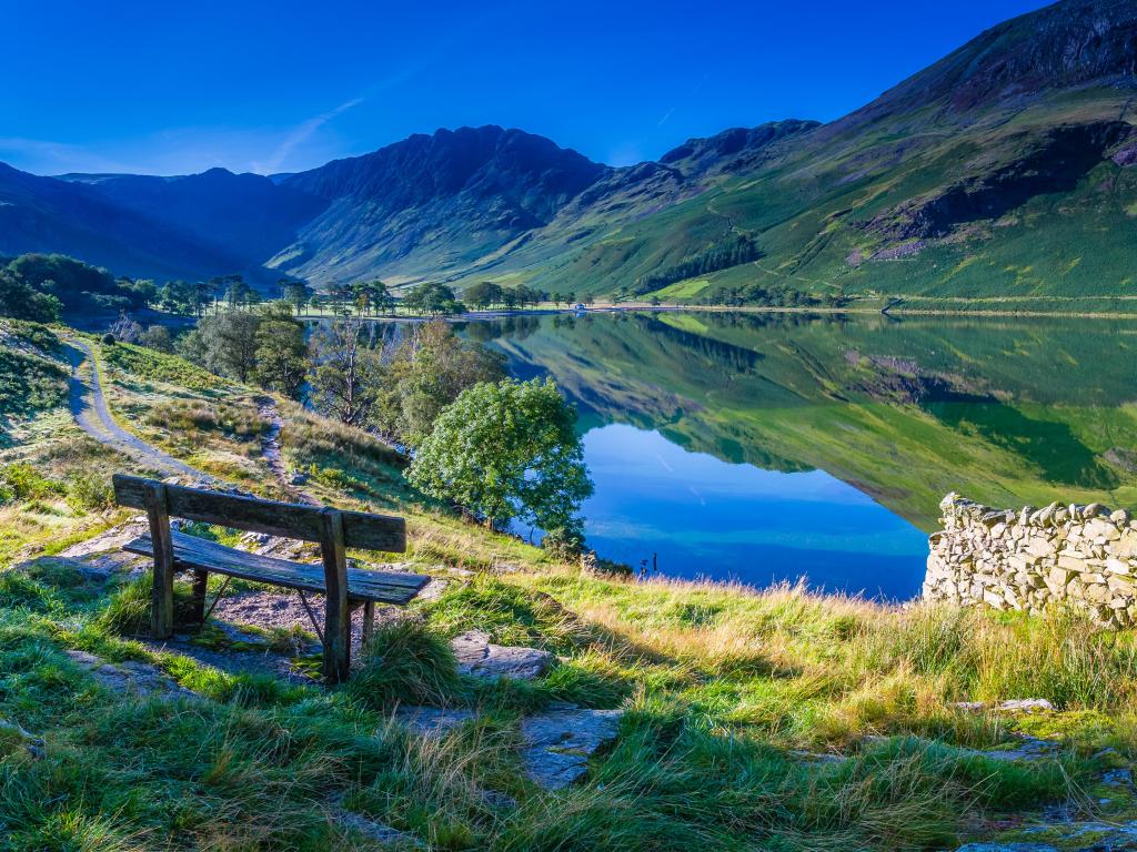 The Lake District, Cumbria, England with a bench overlooking a lake and hills in the distance at Buttermere.