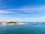 Lighthouse and sailboats under a blue sky day in the Nantucket Harbor.