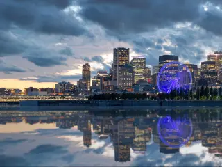Montreal, Canada with the city skyline early in the morning from Mont Royal park and the buildings reflecting the water in the foreground. 