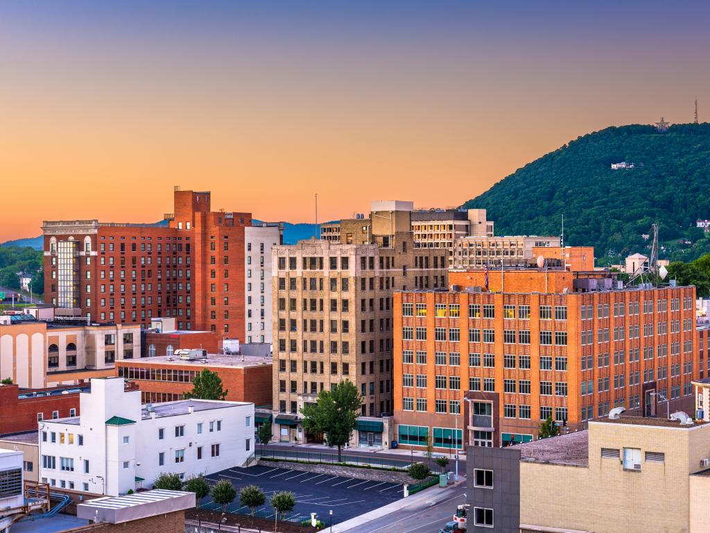 Roanoke, Virginia, USA downtown skyline at dusk with tree covered mountain in the distance.