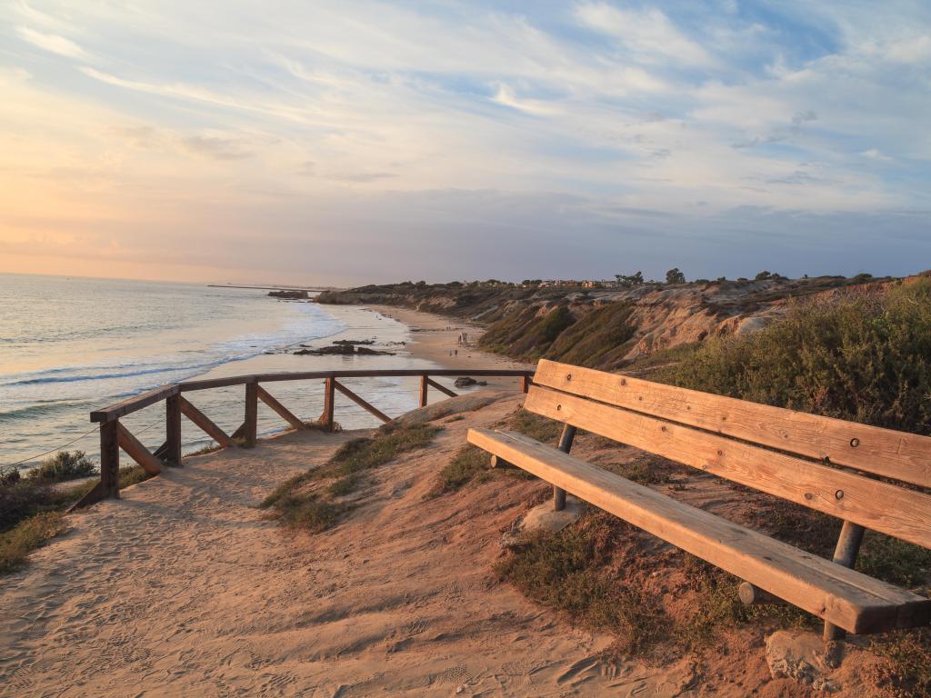 Crystal Cove Beach, California, USA with a bench along an outlook with a view of Crystal Cove Beach, Newport Beach and Laguna Beach line in Southern California