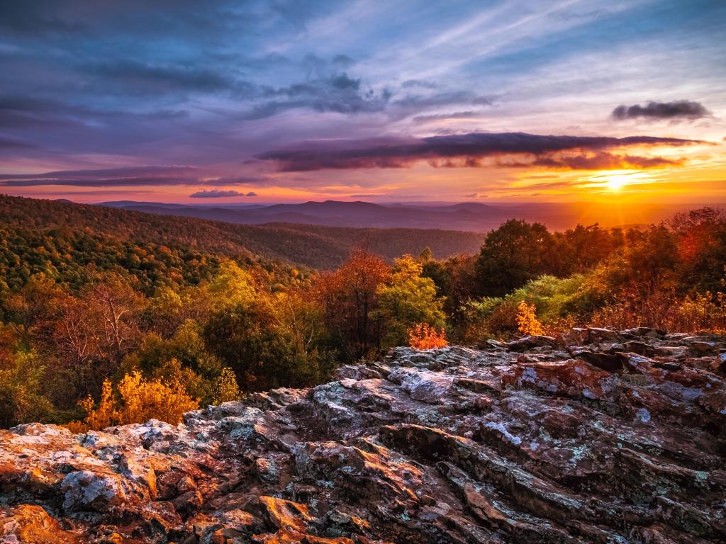 The sun setting in Autumn over mountain peaks and trees