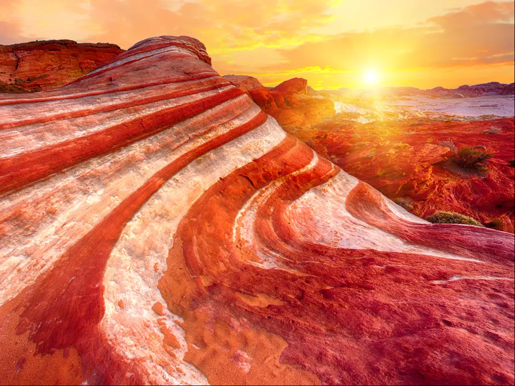 The orange-red sunset illuminating the Fire Wave Rock in Valley of Fire State Park, Nevada