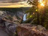 Grand Canyon of Yellowstone National Park, USA taken at sunset with rocky cliffs and the canyon below with a waterfall and trees in the distance. 