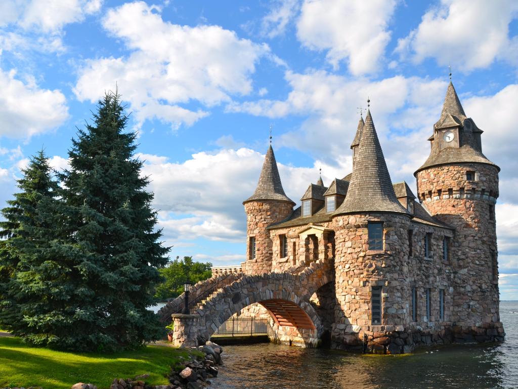 Boldt Castle Power House, One Thousand islands, New York State, USA with trees in the foreground surrounded by sea on a sunny day.