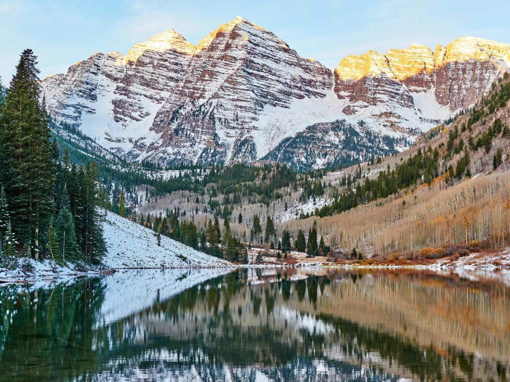 Aspen, Colorado, USA with a view of Maroon Bells morning sunrise reflection with sunlight on peak in Aspen, Colorado rocky mountain and autumn yellow foliage view and winter snow frozen lake.