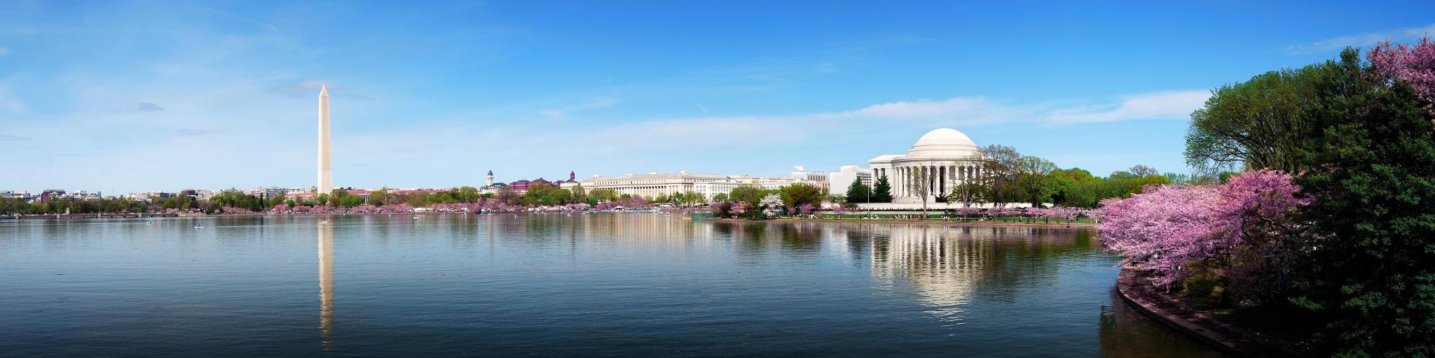 Washington DC, USA with a skyline panorama with Washington monument and Thomas Jefferson memorial on a clear sunny day, water in the foreground.