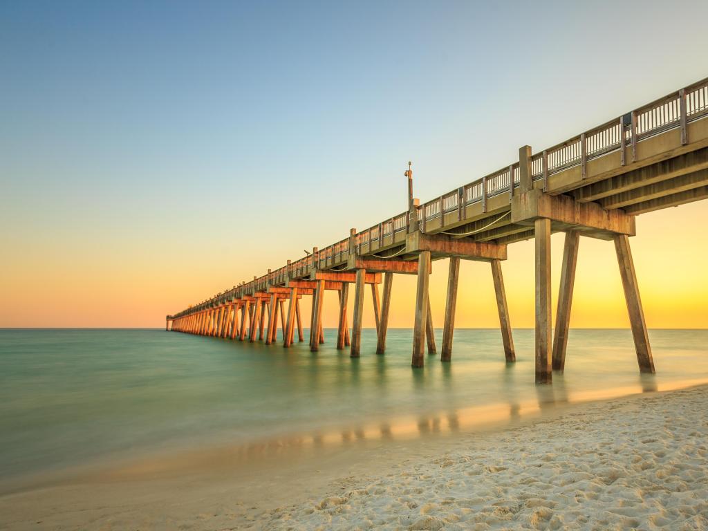Pensacola, Florida, USA with a wooden pier and calm sea, sunset and golden sand. 