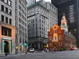 Historic low rise brick built building surrounded by grey sky scrapers