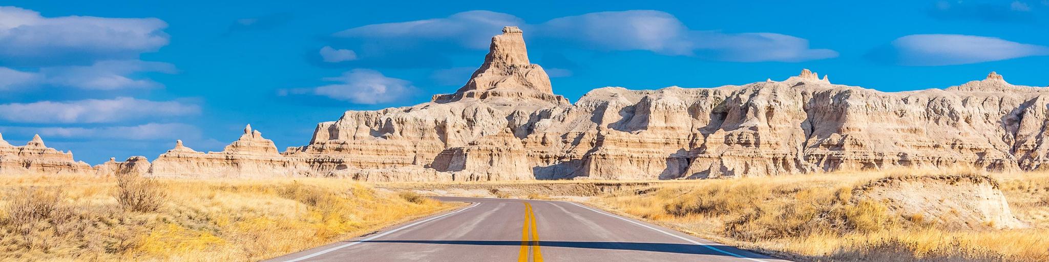Road leading to Badlands National Park, sunny day with blue skies